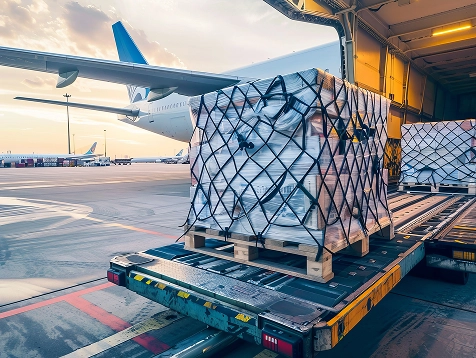 Palety z ładunkiem załadowane do samolotu na lotnisku o zachodzie słońca. Scena oddaje wydajność i globalną logistykę, a w tle widać częściowo zachmurzone niebo.